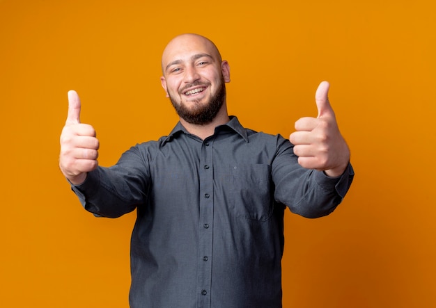 Photo gratuite joyeux jeune homme de centre d'appels chauve montrant les pouces vers le haut isolé sur orange