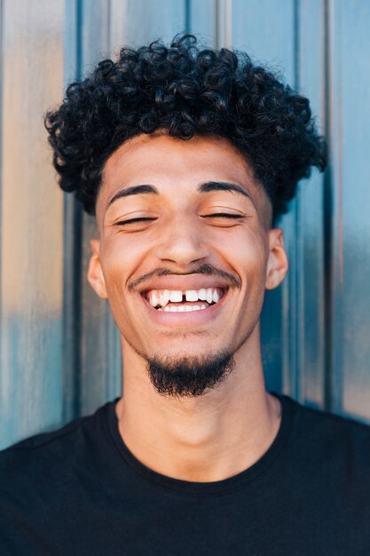 Joyeux jeune homme noir aux cheveux bouclés