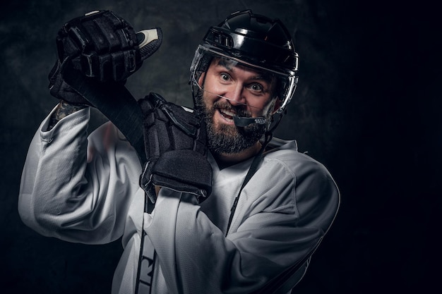 Joyeux joueur de hockey joyeux a une séance photo dans un studio photo sombre.