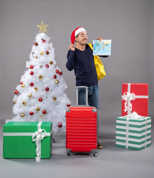 Joyeux Noël homme avec sac à dos jaune debout près de l'arbre de Noël sur fond gris