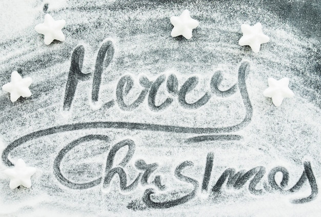 Joyeux Noël inscription entre neige décorative et étoiles