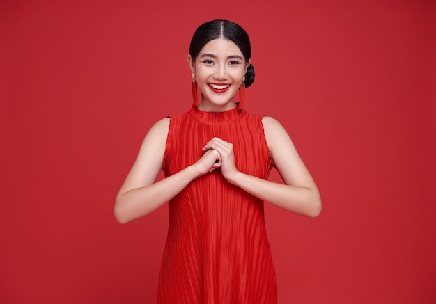 Joyeux nouvel an chinois femme asiatique portant une robe rouge avec un geste de félicitation