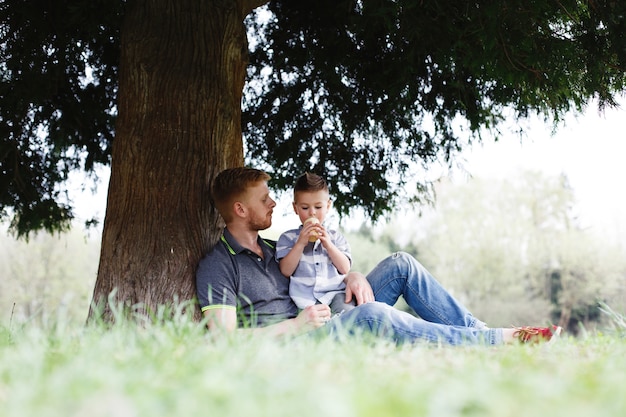 Joyeux papa et fils s&#39;amuser à jouer sous l&#39;arbre dans le parc