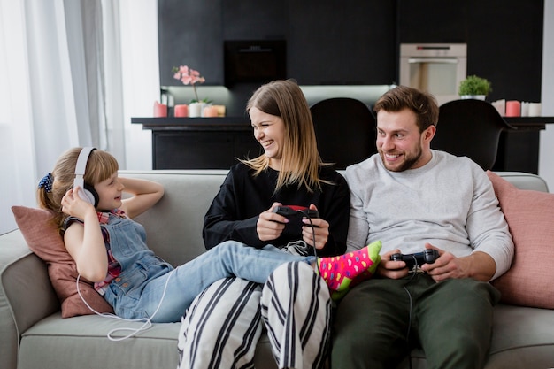 Joyeux parents jouant à des jeux vidéo près de la fille