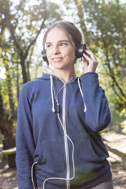 Joyful jeune femme avec sweat à capuche et d&#39;écouteurs