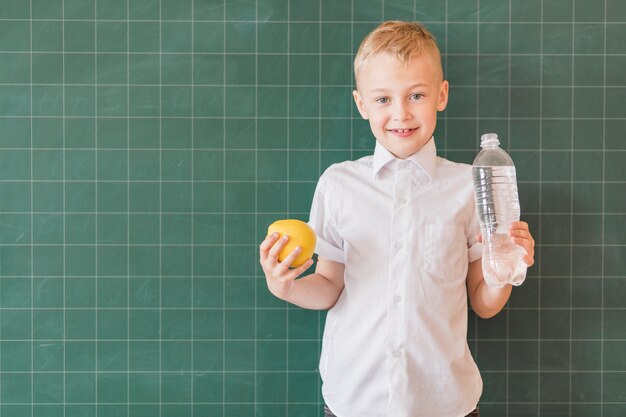 Junior avec eau et pomme près du tableau