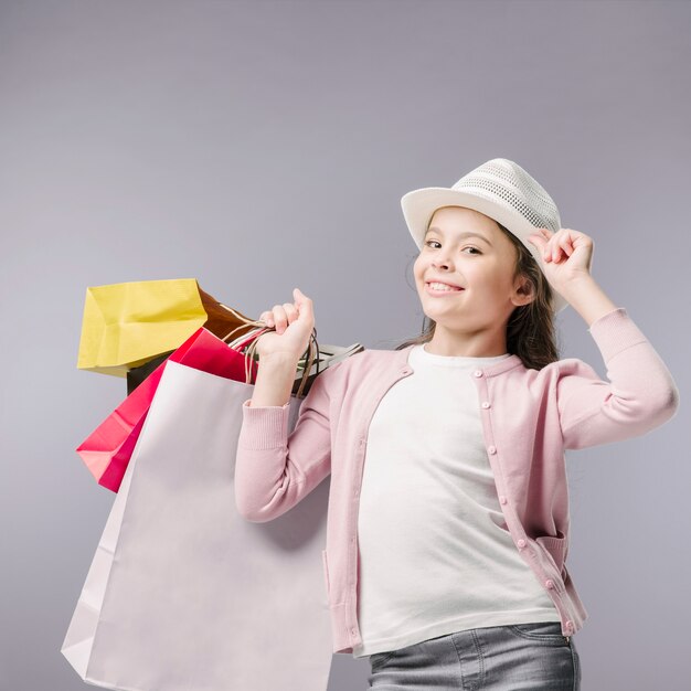 Junior posant avec des sacs à provisions et un chapeau