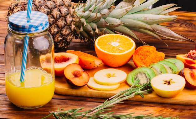 Jus bocal avec des tranches de fruits sur une planche à découper et du romarin