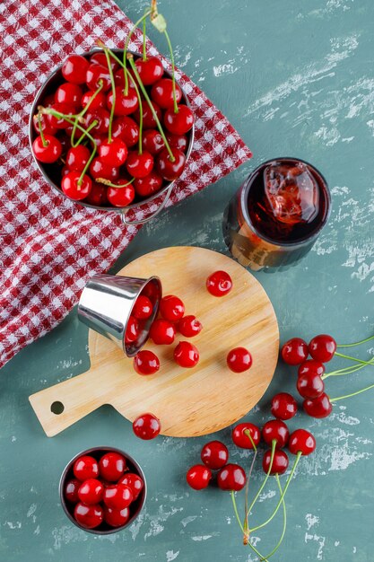 Jus de cerises, planche à découper dans une cruche sur plâtre et torchon, vue de dessus.