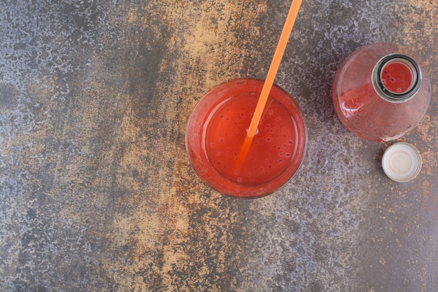 Photo gratuite jus de fraise frais avec de la paille et une bouteille sur une surface en marbre