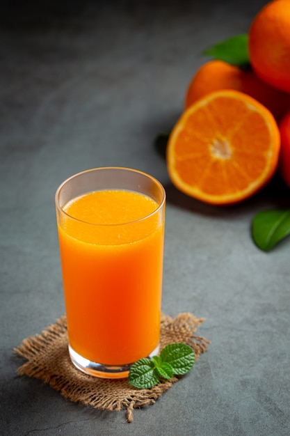 Jus d'orange frais dans le verre sur fond sombre