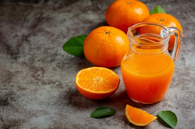 Jus d'orange frais dans le verre sur fond sombre