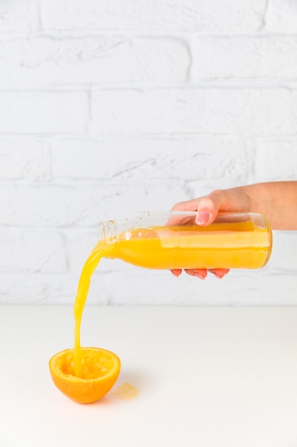 Jus d&#39;orange versé dans une orange vide