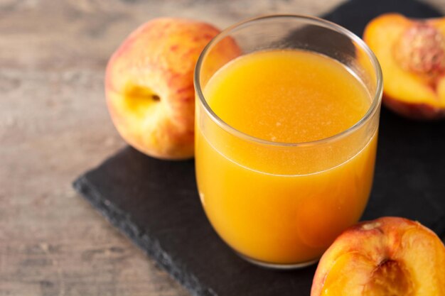 Jus de pêche naturel en verre sur table en bois