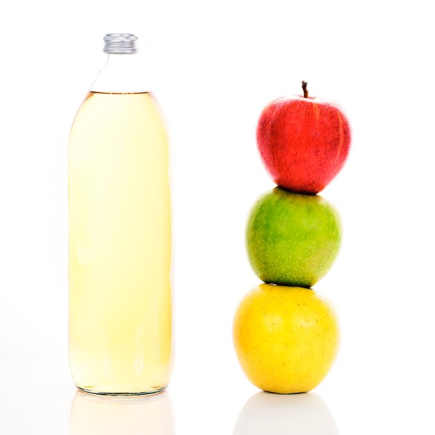 Jus de pomme en bouteille en verre et trois pommes mûres