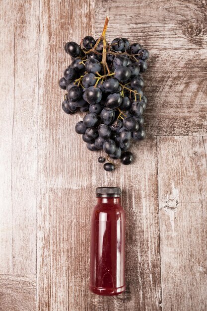 Jus de raisin en bouteille à côté d'un brunch de raisin sur fond de bois. Mode de vie sain