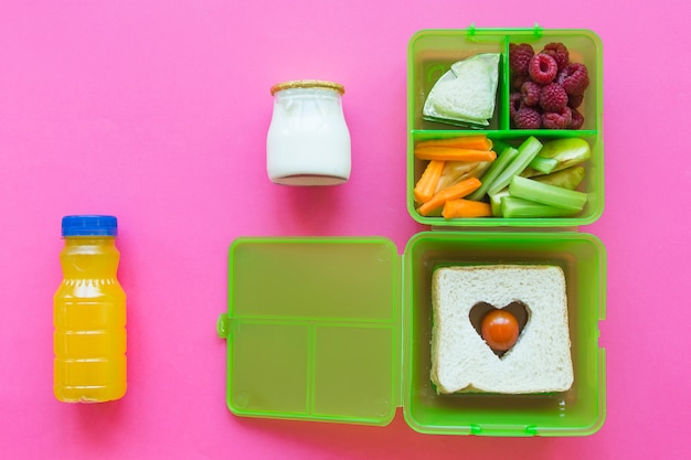 Jus et yogourt près de la boîte à lunch avec de la nourriture