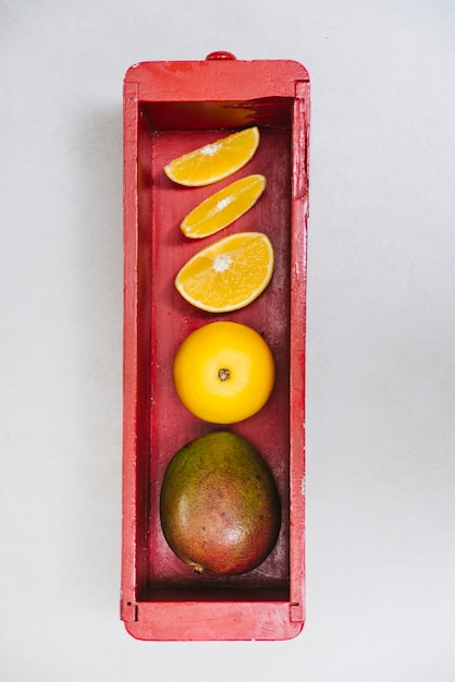 Photo gratuite juteux citron vert et mangue dans un contenant en bois sur fond blanc