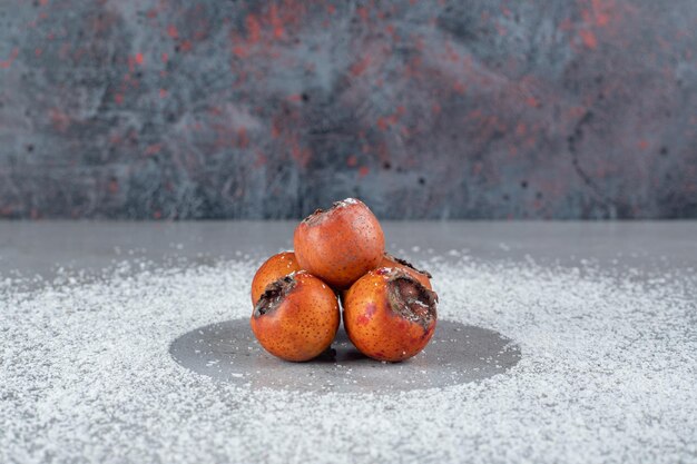 Kakis avec de la poudre de noix de coco éparpillés sur une surface en marbre