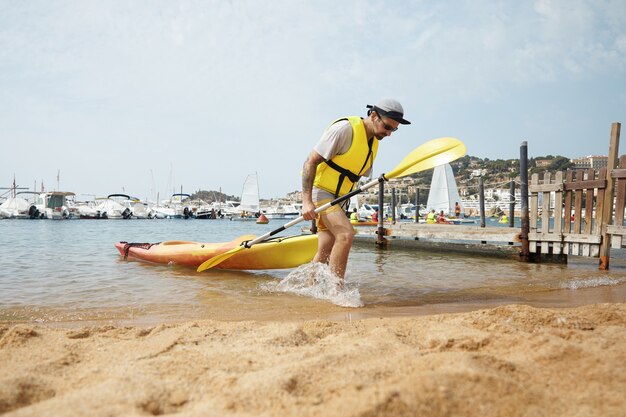 Kayak homme en casquette et veste de sécurité jaune
