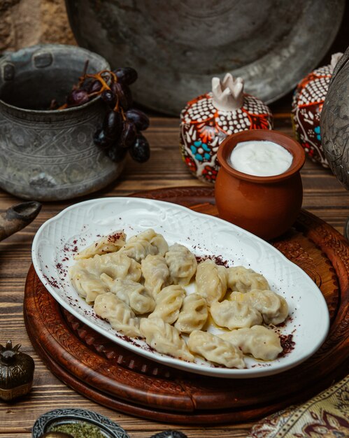 Khinkali géorgien à l'intérieur d'une assiette blanche avec du yaourt.