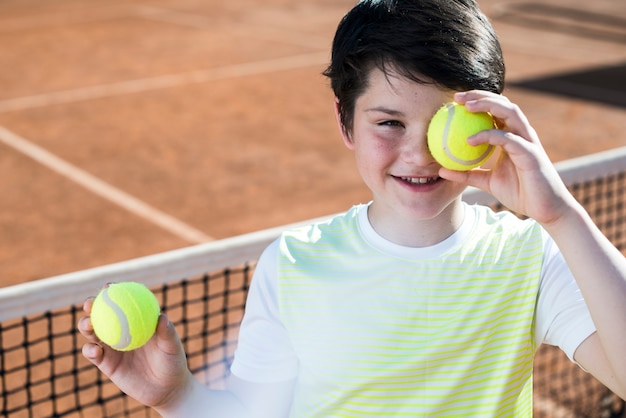 Kid couvrant ses yeux avec une balle de tennis