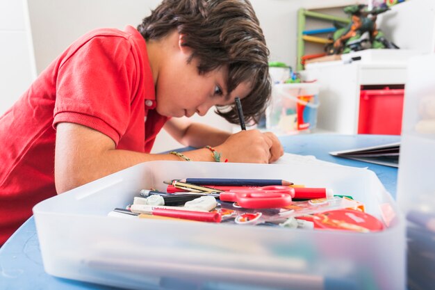 Kid dessin près de la boîte de papeterie