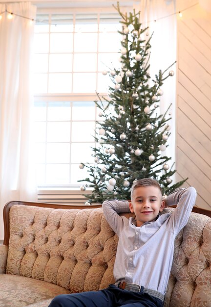 Kid est assis sur le canapé à Noël