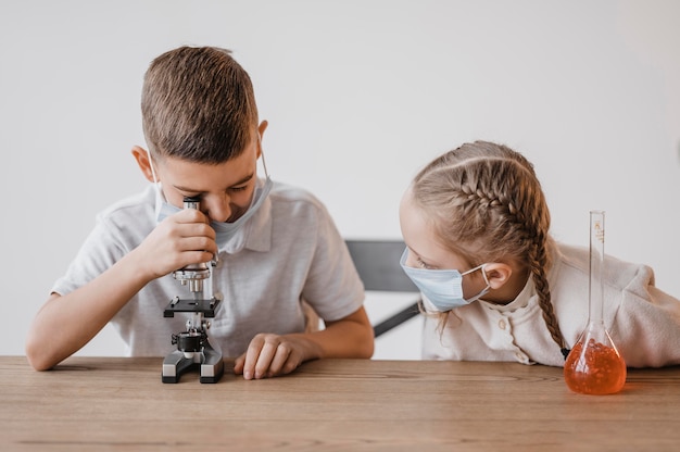 Kid avec masque médical regardant à travers un microscope