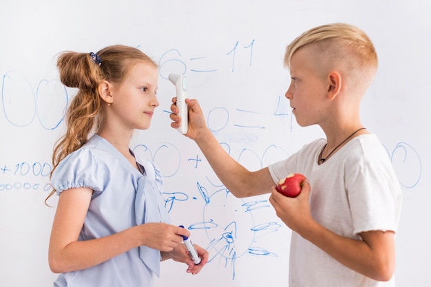 Photo gratuite kid prenant la température d'un collègue