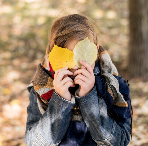 Kid shot moyen couvrant le visage avec des feuilles