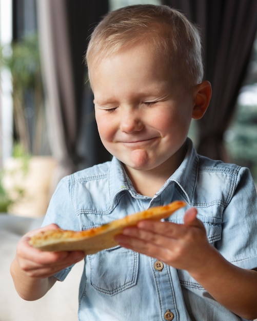 Photo gratuite kid smiley coup moyen avec tranche de pizza