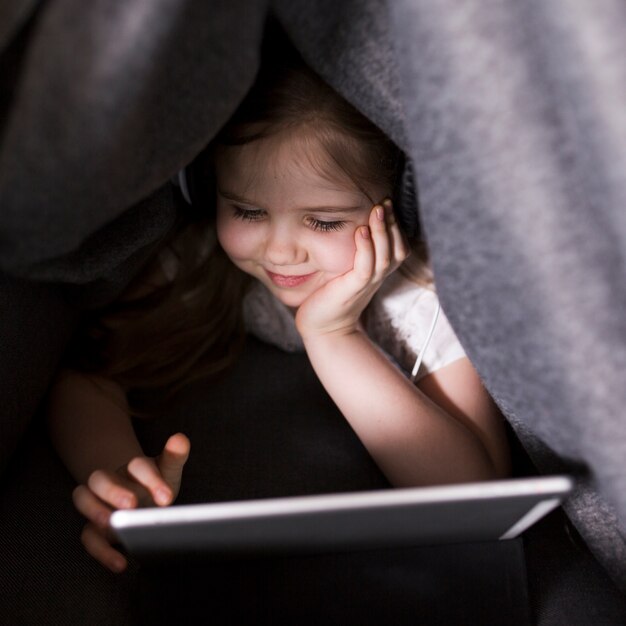 Kid avec tablette sous couverture