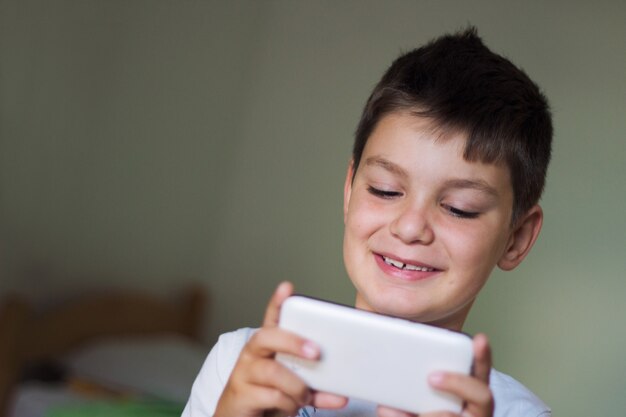 Kid utilisant un téléphone intelligent mobile et souriant