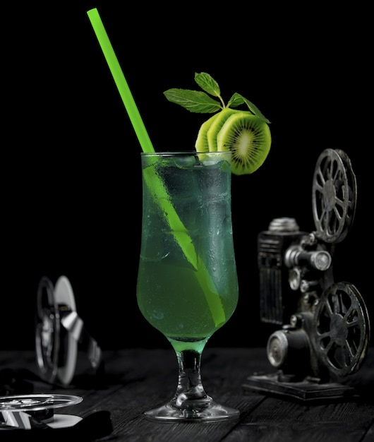 Kiwi alcool cocktail avec des tranches de fruits et une pipe verte.