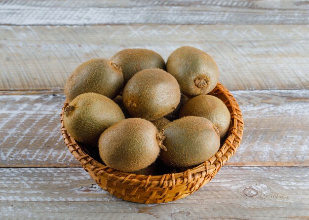 Kiwi dans un panier en osier sur une table en bois. vue grand angle.