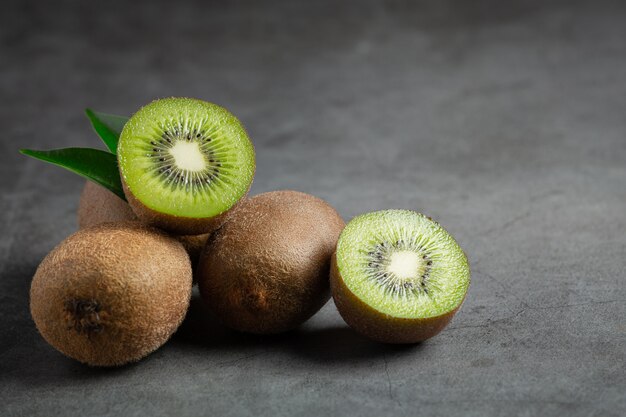 Kiwi frais, coupé en deux, posé sur un sol sombre