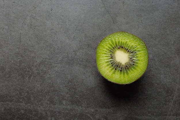 Kiwi frais, coupé en deux, posé sur un sol sombre