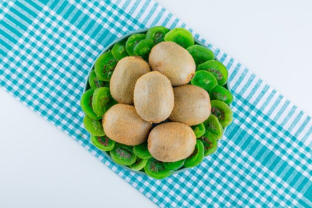 Kiwi frais dans une assiette avec plat de kiwi séché poser sur fond de tissu blanc et pique-nique