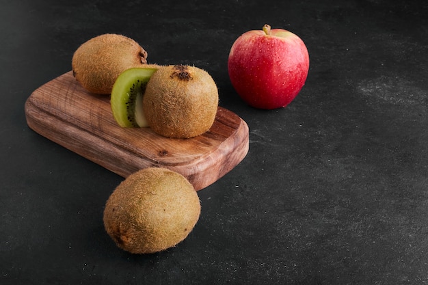 Kiwi et pommes sur planche de bois.