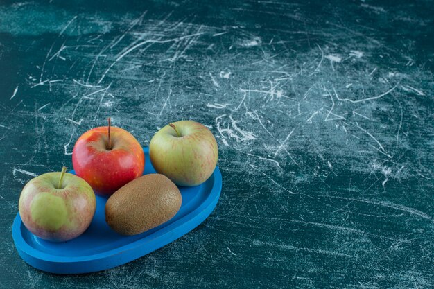 Kiwi et pommes sur plaque de bois , sur la table en marbre.