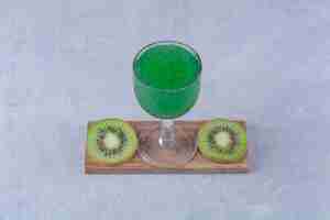 Photo gratuite kiwi tranché et jus de kiwi sur une planche sur une table en marbre.