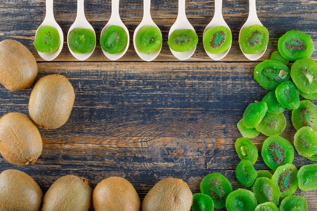 Kiwi avec des tranches séchées à plat sur un fond en bois