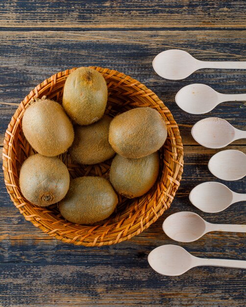 Les kiwis dans un panier en osier avec des cuillères à plat poser sur un fond en bois