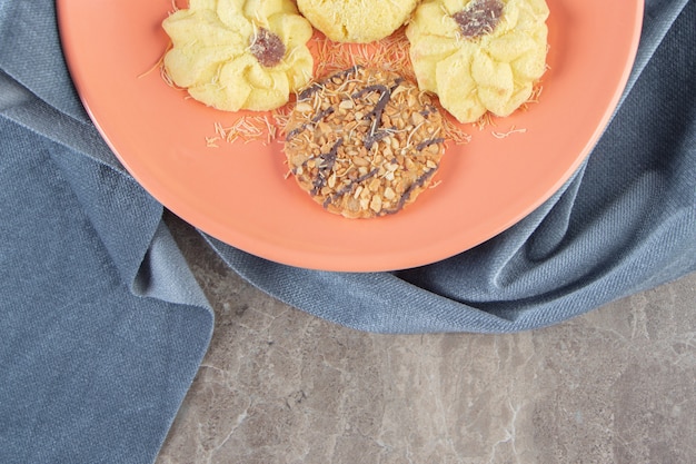 Photo gratuite kue semprit et cookie sur une assiette sur une serviette sur du marbre.