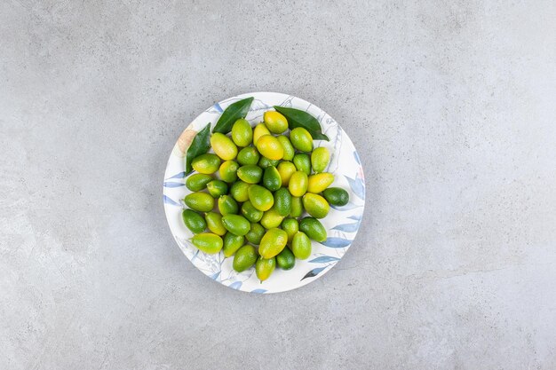 Kumquats et feuilles sur une assiette en fond de marbre. Photo de haute qualité