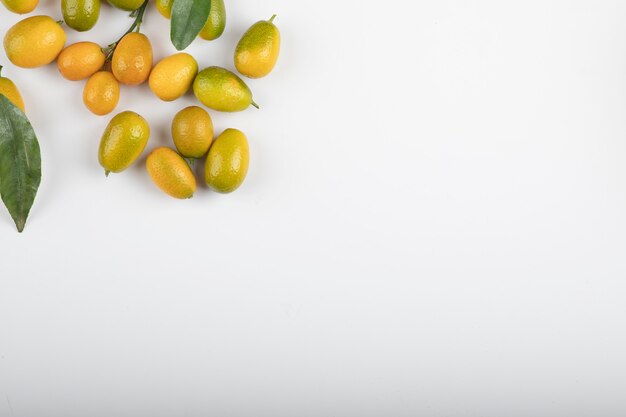 Kumquats mûrs frais avec des feuilles sur blanc.