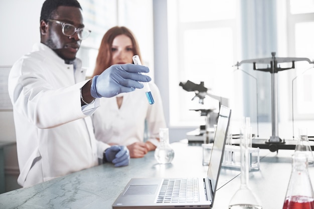 Les Laboratoires De Laboratoire Mènent Des Expériences Dans Un Laboratoire De Chimie Dans Des Flacons Transparents. Formules De Sortie.