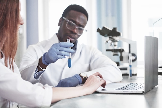 Les laboratoires de laboratoire mènent des expériences dans un laboratoire de chimie dans des flacons transparents. Formules de sortie.