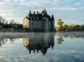 Photo gratuite lac clair avec le reflet d'un immense château contre le ciel nuageux en automne